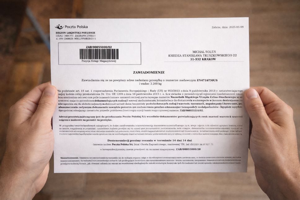 Osoba trzyma list od Poczty Polskiej z polskim tekstem o odprawie celnej paczek, zawierający kod kreskowy, dane adresowe i oświadczenie o powiadomieniu, widziany z góry na jednolitym tle.